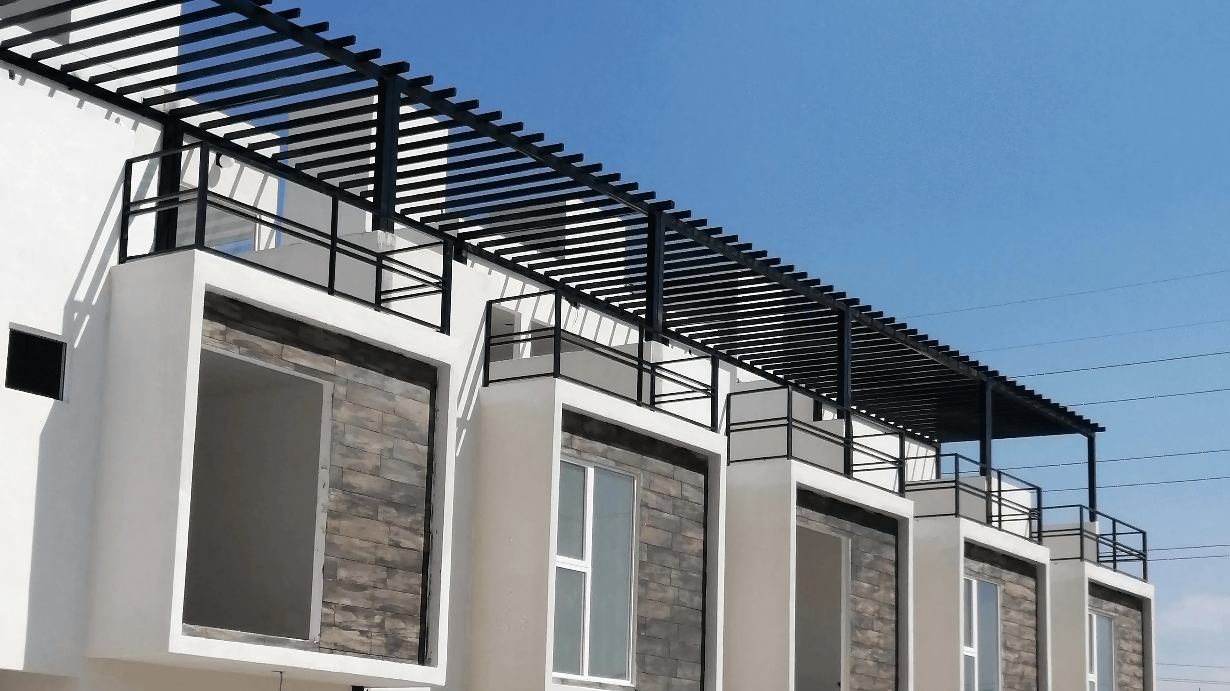 Pérgola y barandales de herrería instalados en la azotea de una fila de casas en Tijuana